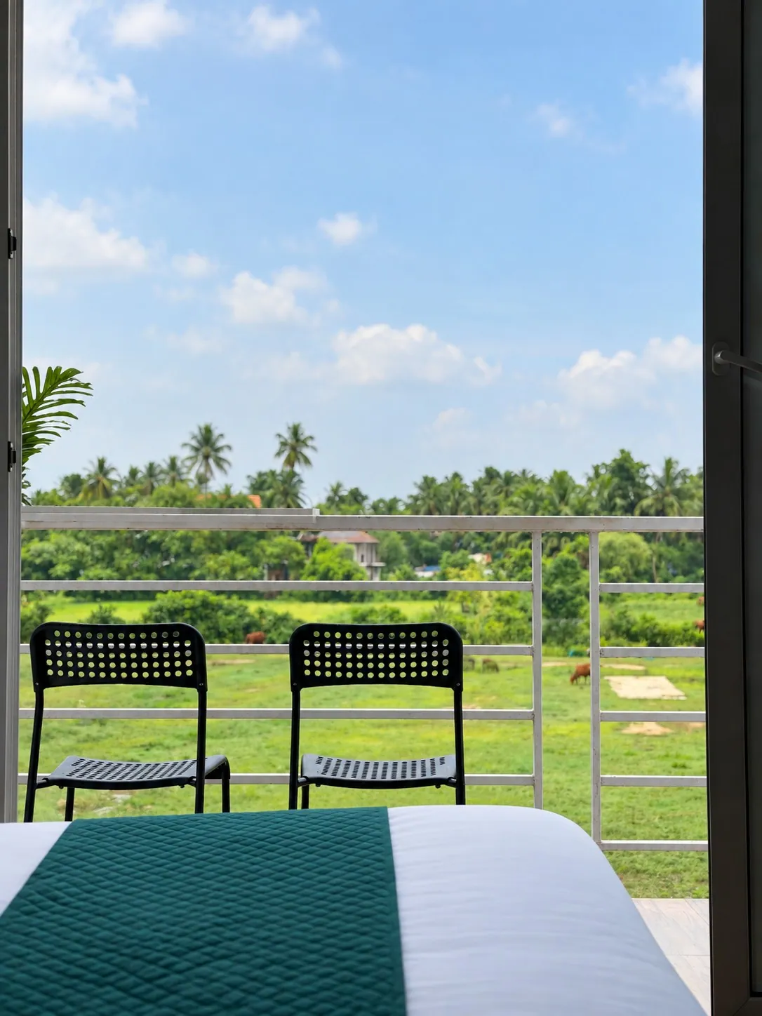 The two balcony chairs looking out over the fields, seen past the foot of the bed