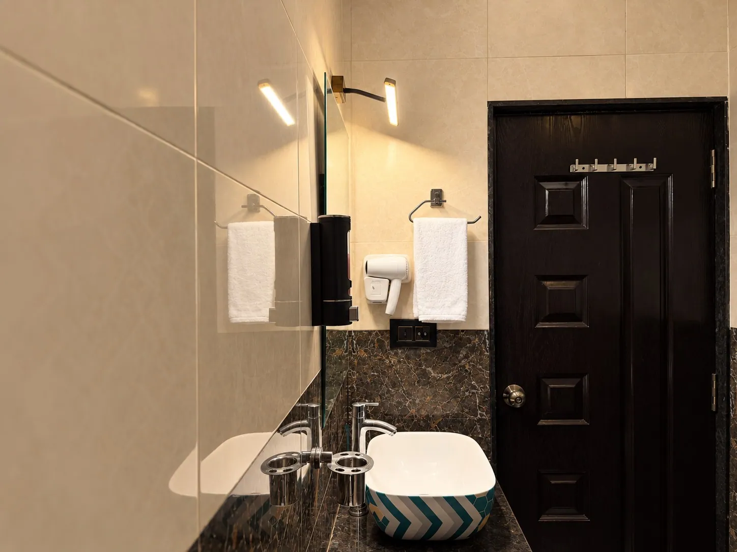 The basin, fresh towels and mirror lights beside the glass shower screen
