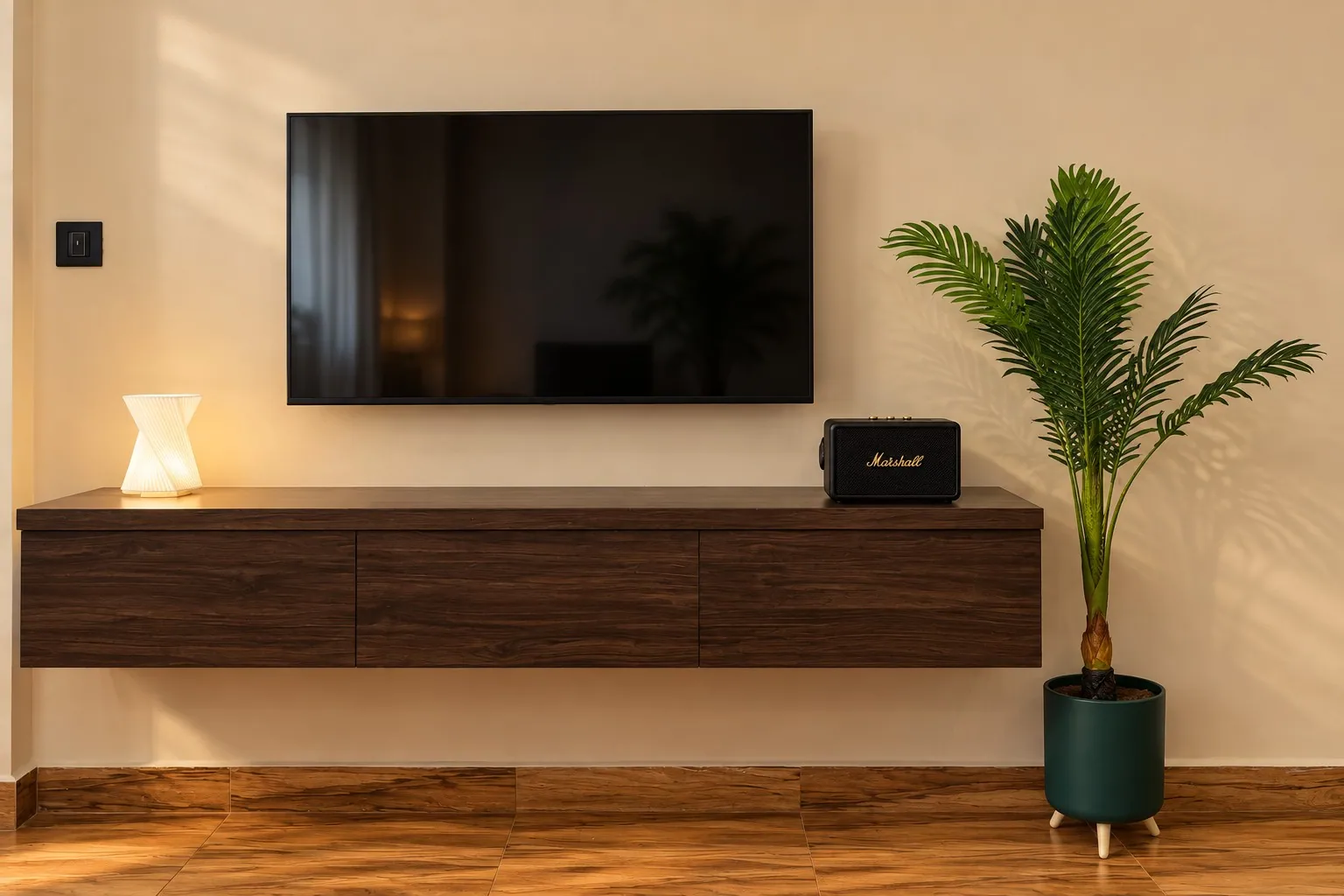 The wall-mounted TV over a floating walnut console with a Marshall speaker and a lamp