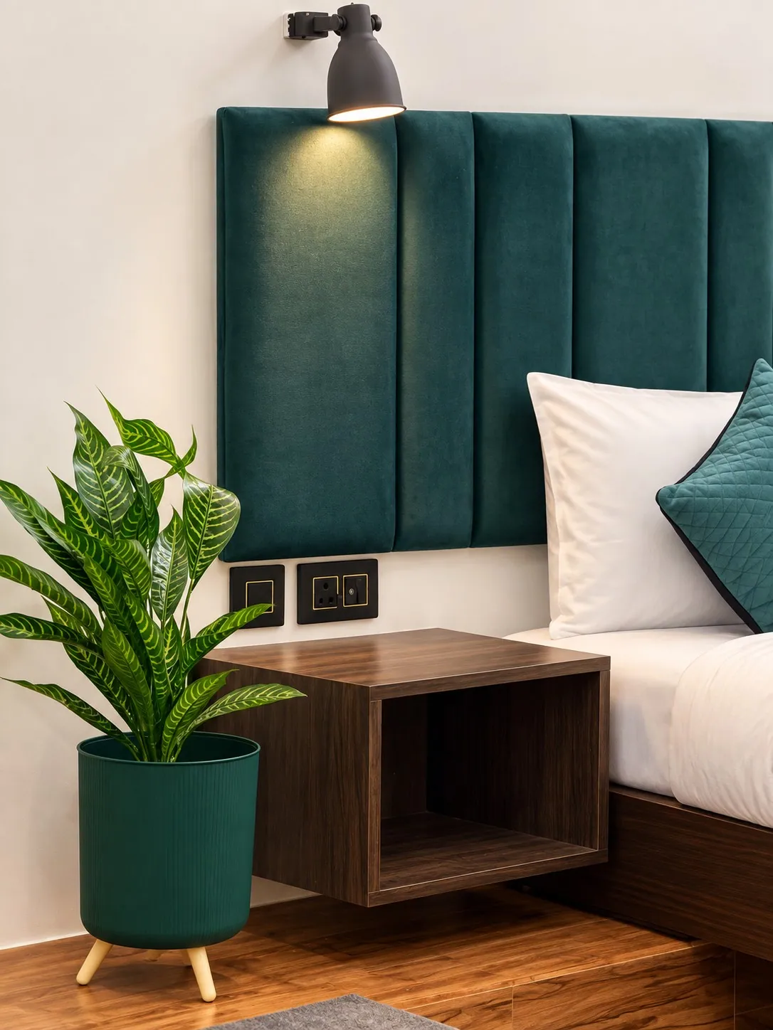 A floating walnut nightstand beside the bed, with a plant in a green pot