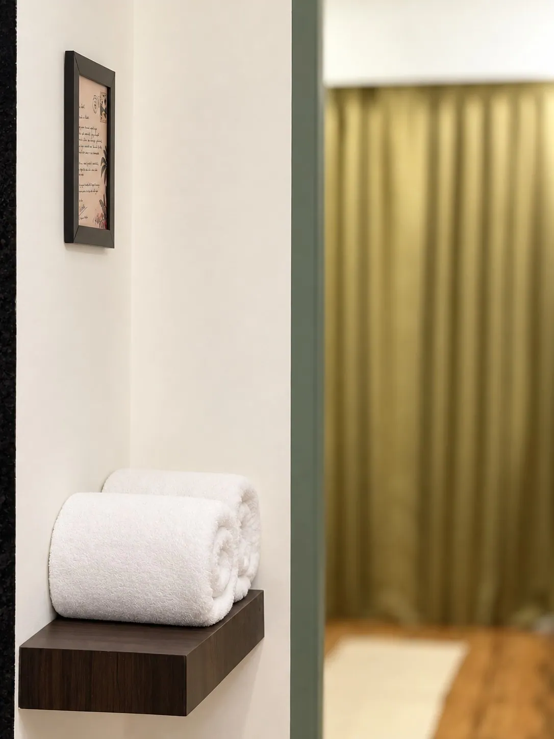 Rolled white towels on a walnut shelf in the hallway