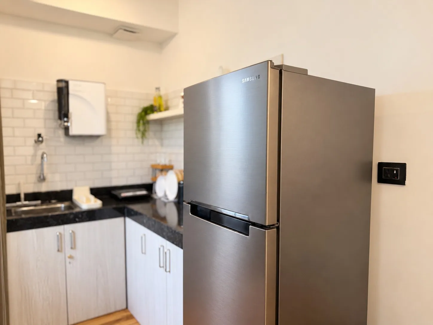 The tall fridge beside the kitchen counter and sink